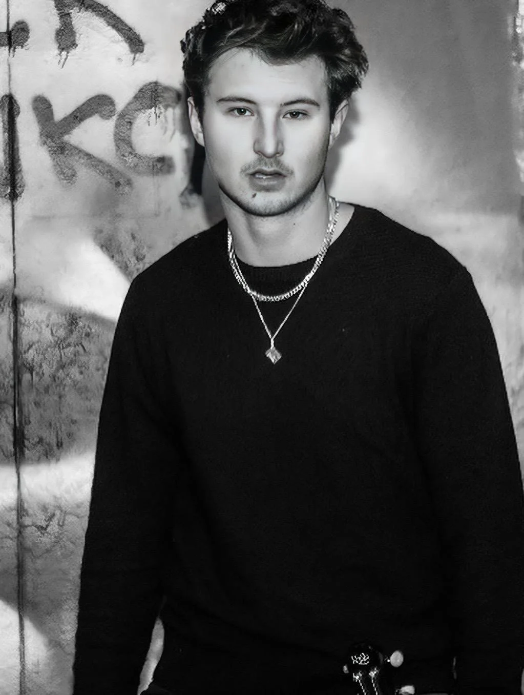 Black and white portrait of Liam C in front of graffiti